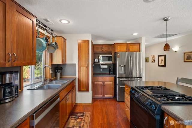 kitchen with dark wood-type flooring, sink, pendant lighting, appliances with stainless steel finishes, and a textured ceiling