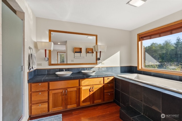 bathroom featuring vanity, hardwood / wood-style flooring, and tiled tub