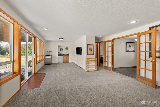 unfurnished living room with french doors, carpet, and a textured ceiling