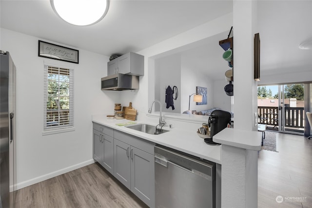 kitchen featuring appliances with stainless steel finishes, kitchen peninsula, sink, and a wealth of natural light