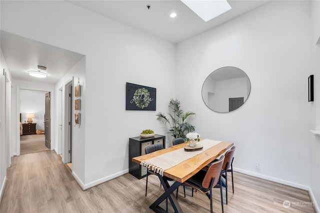 dining area with light hardwood / wood-style floors and a skylight