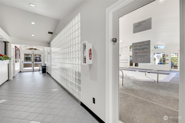 hall featuring light carpet, lofted ceiling, and plenty of natural light