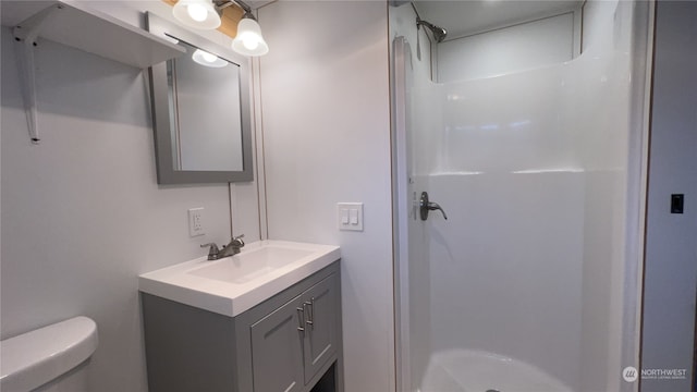 bathroom featuring vanity, toilet, and walk in shower