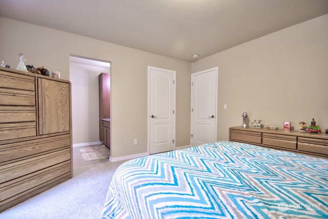 bedroom featuring ensuite bathroom and light colored carpet