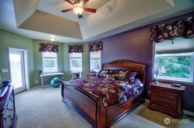 carpeted bedroom featuring ceiling fan and a tray ceiling