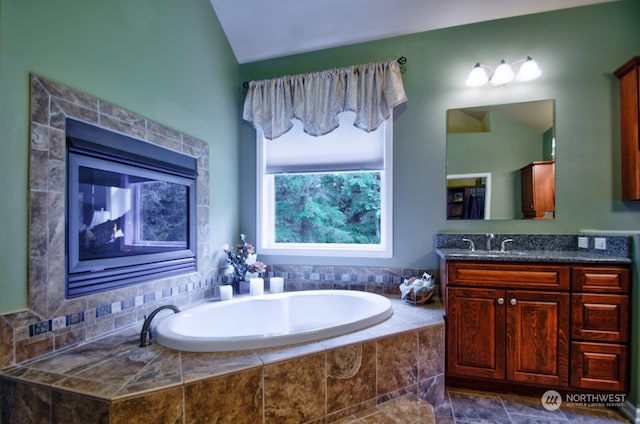 bathroom with vanity, lofted ceiling, and tiled tub