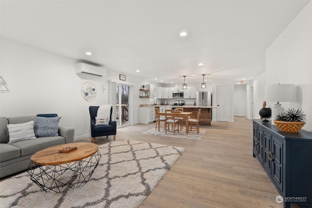 living room with a wall mounted air conditioner, light hardwood / wood-style floors, and sink