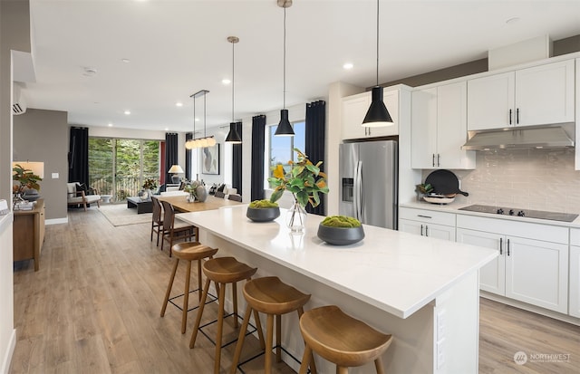 kitchen featuring white cabinets, hanging light fixtures, stainless steel fridge with ice dispenser, light hardwood / wood-style flooring, and black electric cooktop