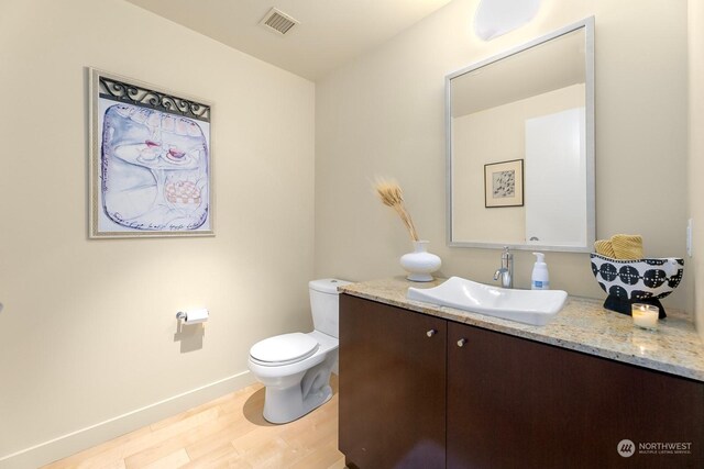 909 5th Ave Unit 2103, Seattle, WA 98104 - bathroom featuring toilet, vanity, wood finished floors, and baseboards