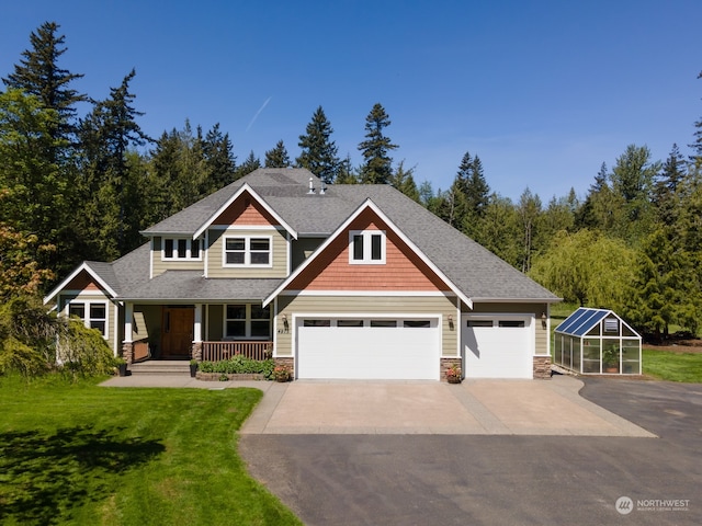 craftsman-style house with a garage, an outdoor structure, a front yard, and covered porch