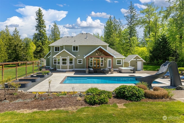 back of property featuring an outbuilding, a swimming pool with hot tub, a yard, and a patio area