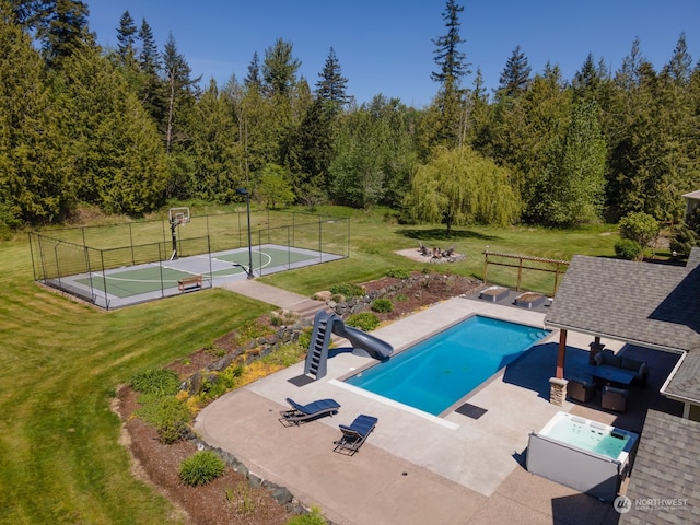 view of swimming pool with a yard, tennis court, and a water slide