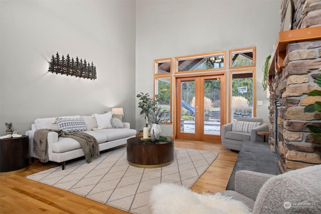 living room featuring french doors, a high ceiling, and light wood-type flooring