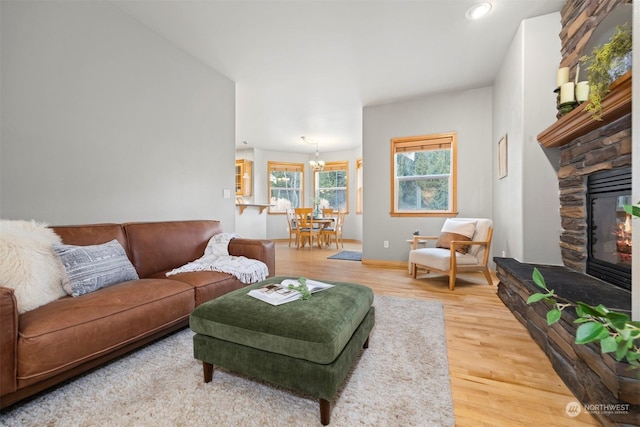 living room with a stone fireplace, hardwood / wood-style floors, and a notable chandelier