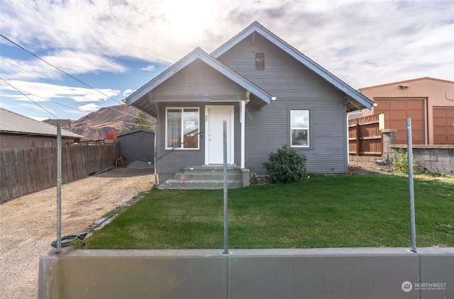 bungalow-style house with a storage shed and a front lawn