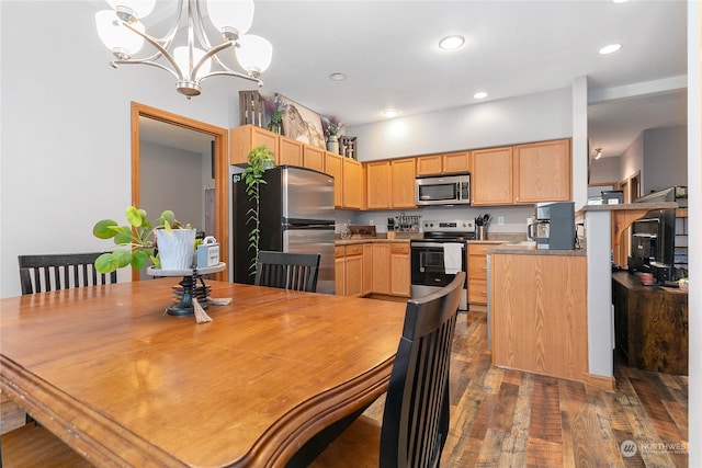 kitchen with light brown cabinets, dark hardwood / wood-style floors, stainless steel appliances, and hanging light fixtures