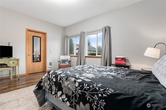 bedroom with dark wood-type flooring and heating unit