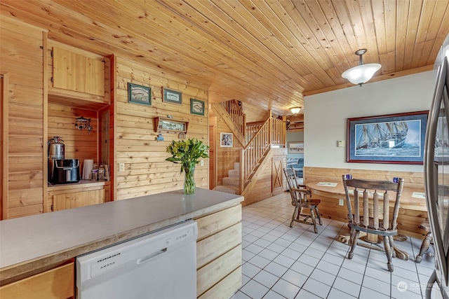 kitchen featuring light brown cabinets, wooden walls, wooden ceiling, white dishwasher, and light tile patterned floors