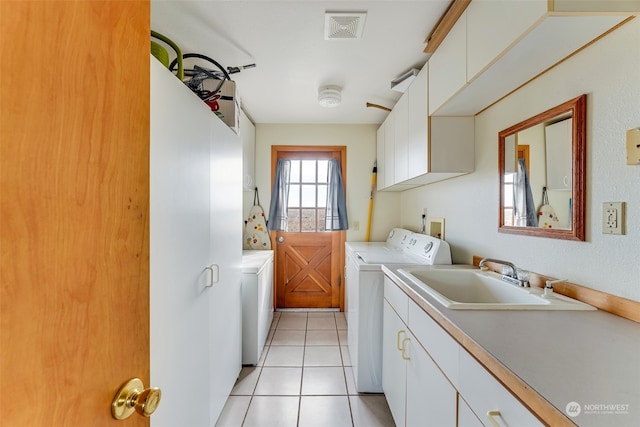 clothes washing area featuring sink, independent washer and dryer, light tile patterned floors, and cabinets