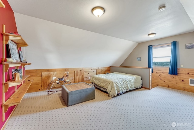 bedroom featuring vaulted ceiling, carpet flooring, and wood walls