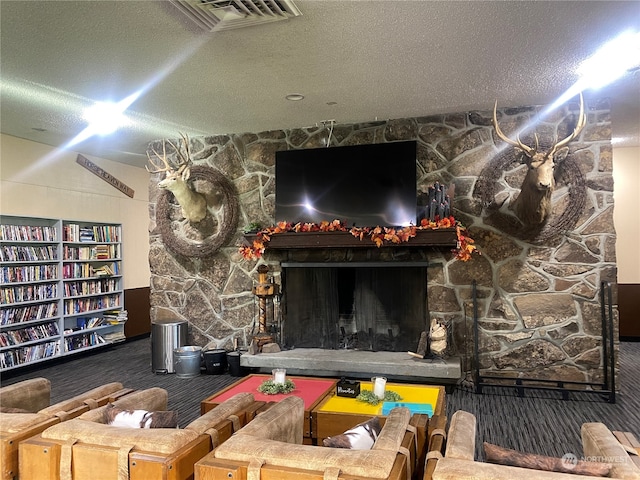 carpeted living room featuring a stone fireplace and a textured ceiling