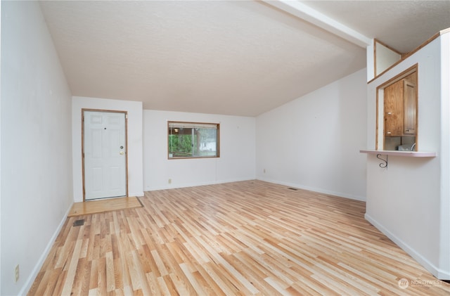 interior space with a textured ceiling, light hardwood / wood-style floors, and vaulted ceiling