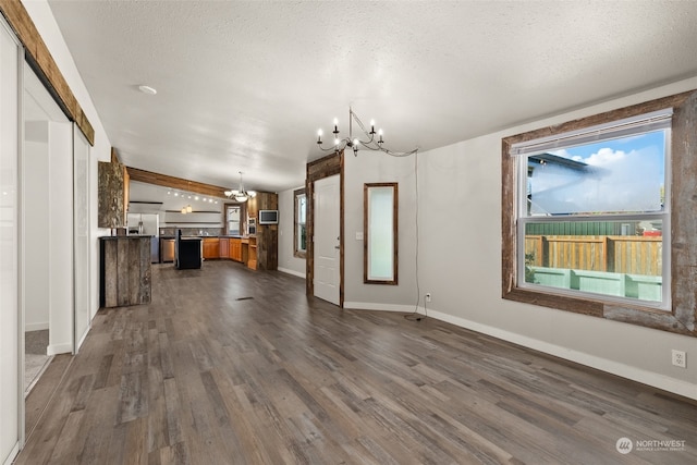 unfurnished living room with beam ceiling, a textured ceiling, dark hardwood / wood-style floors, and a chandelier