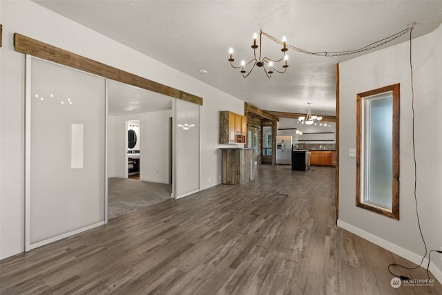 unfurnished living room featuring a textured ceiling, a chandelier, and dark hardwood / wood-style floors