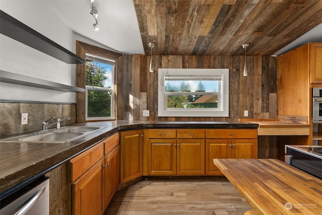 kitchen with sink, light wood-type flooring, dishwasher, vaulted ceiling, and decorative backsplash