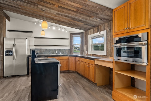 kitchen featuring lofted ceiling, pendant lighting, appliances with stainless steel finishes, and hardwood / wood-style flooring