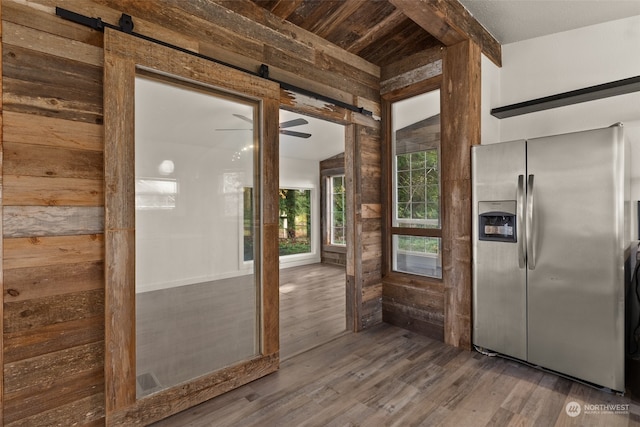 entryway featuring wood walls, a barn door, hardwood / wood-style flooring, and ceiling fan