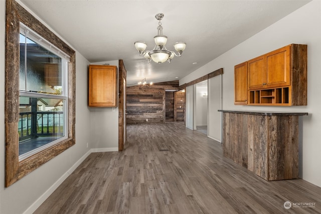 interior space with dark hardwood / wood-style floors, wooden walls, a wealth of natural light, and vaulted ceiling