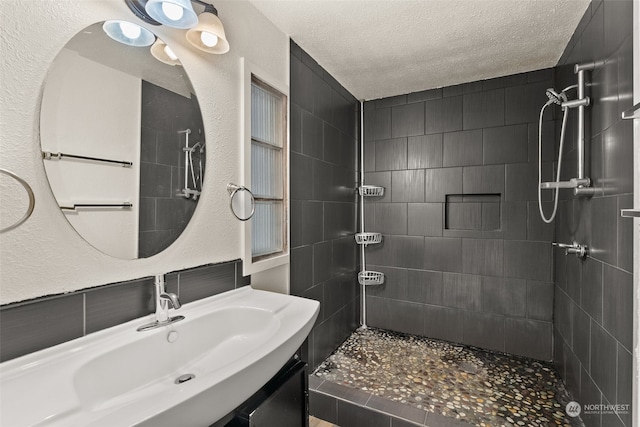 bathroom with vanity, a textured ceiling, and tiled shower