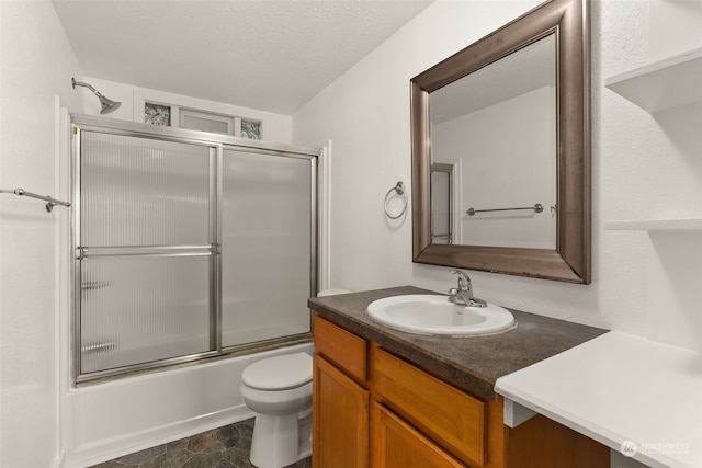 full bathroom featuring vanity, a textured ceiling, toilet, and shower / bath combination with glass door