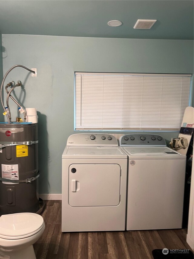 washroom with secured water heater, washing machine and dryer, and dark hardwood / wood-style floors