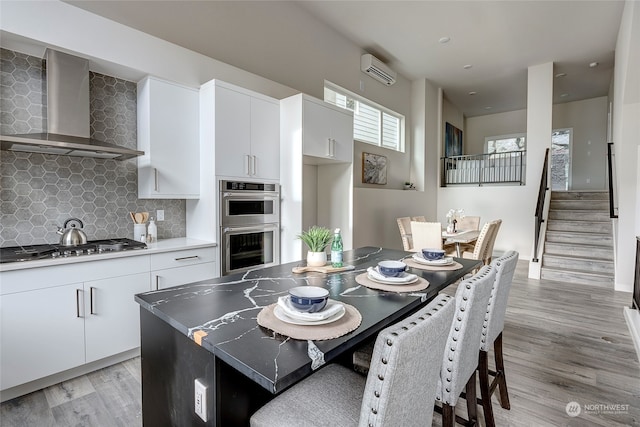 dining area with stairs, a wall mounted AC, and light wood-style floors