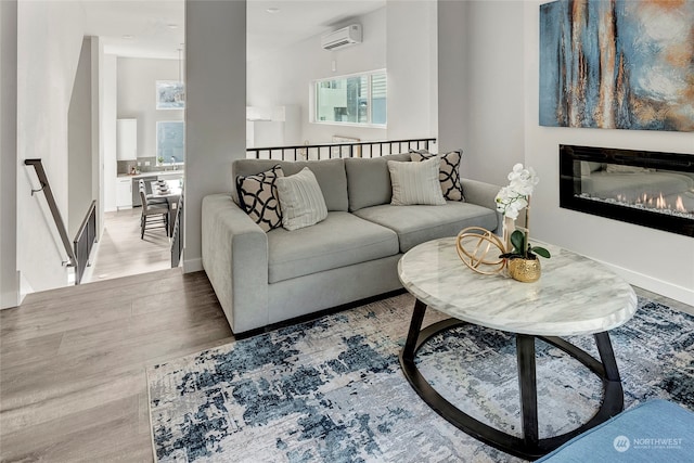 living room with a glass covered fireplace, wood finished floors, and a wall mounted AC