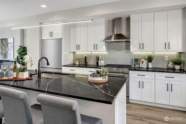 kitchen featuring stainless steel appliances, sink, wall chimney range hood, and white cabinets