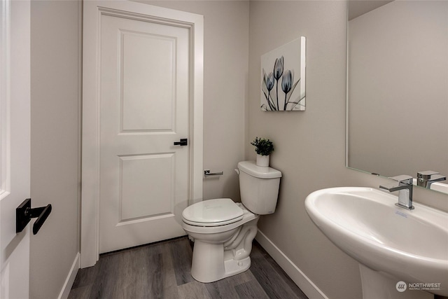 bathroom with toilet, sink, and hardwood / wood-style floors