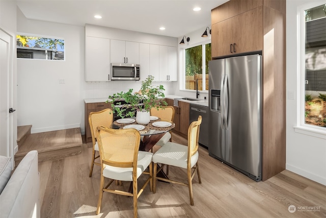 kitchen with white cabinetry, stainless steel appliances, and light wood-type flooring