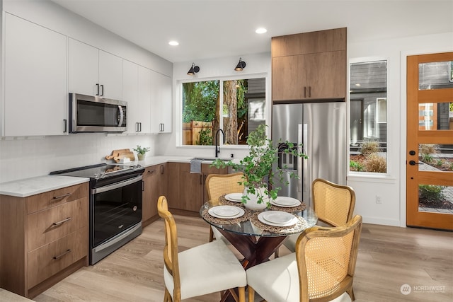 kitchen featuring light hardwood / wood-style flooring, stainless steel appliances, backsplash, sink, and white cabinets