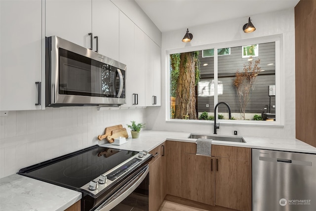 kitchen featuring white cabinetry, stainless steel appliances, sink, and light stone counters