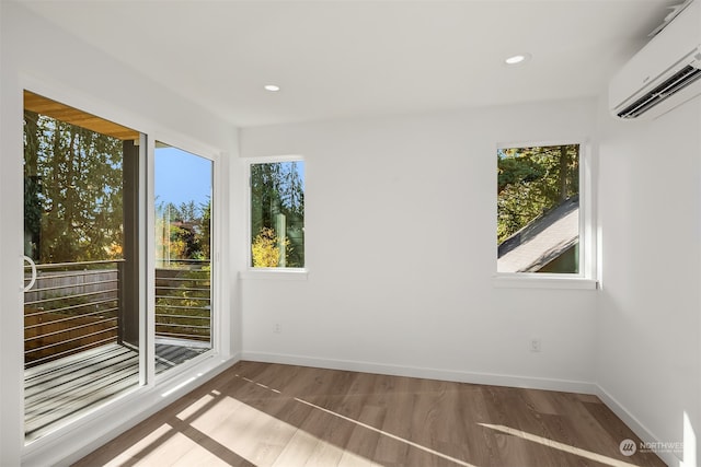 spare room with a healthy amount of sunlight, an AC wall unit, and wood-type flooring