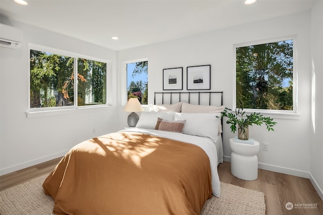 bedroom featuring light hardwood / wood-style flooring and a wall unit AC