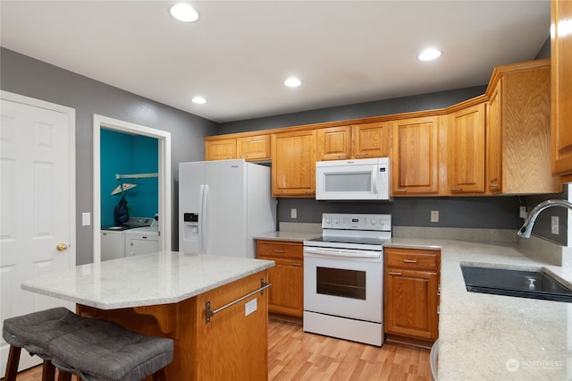 kitchen with a kitchen island, light hardwood / wood-style flooring, sink, separate washer and dryer, and white appliances