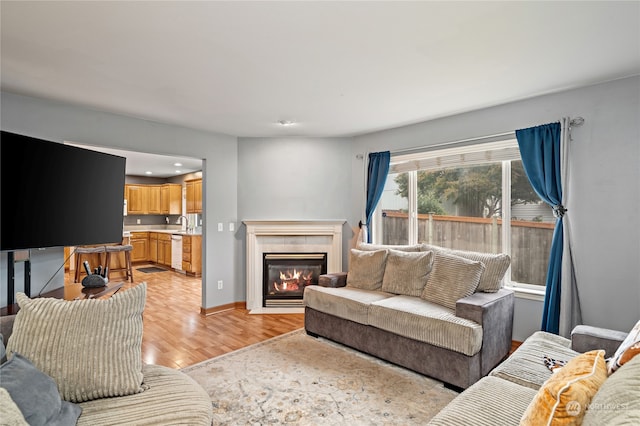 living room with light hardwood / wood-style flooring, sink, and a tile fireplace