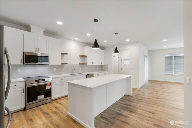 kitchen with white cabinetry, appliances with stainless steel finishes, light hardwood / wood-style flooring, and hanging light fixtures