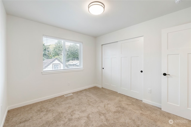 unfurnished bedroom featuring light carpet and a closet