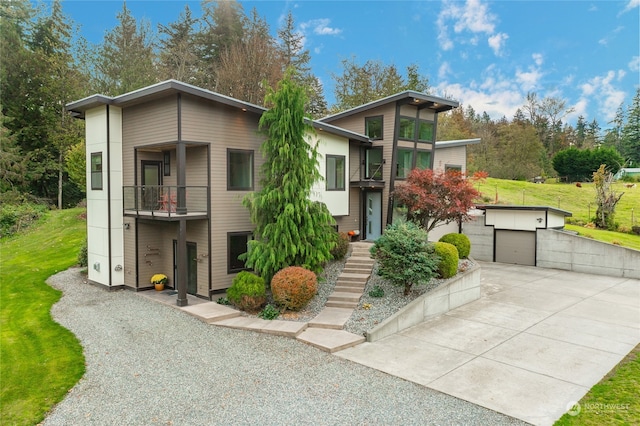 contemporary house featuring a front yard, a balcony, and a garage