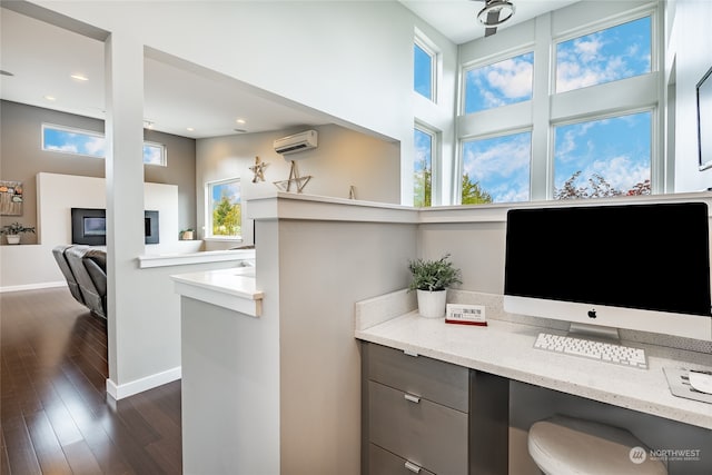 office space featuring built in desk, a wall unit AC, and dark hardwood / wood-style flooring